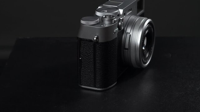 Silver and black vintage style digital mirrorless camera with lens on a dark background