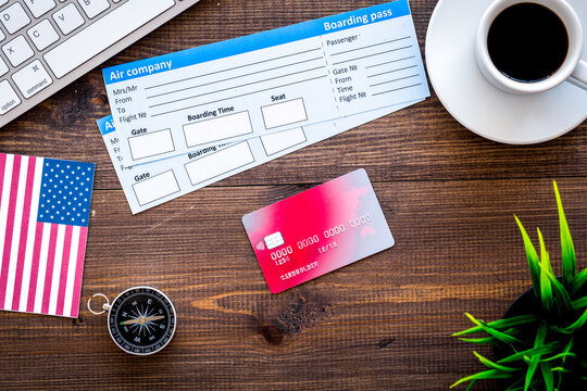 booking trip with tickets, flags and tourist outfit on wooden office desk background top view