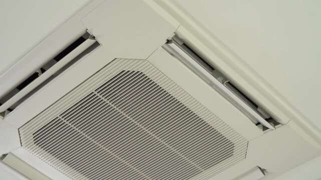 Close up low angle view of a white ceiling mounted cassette air conditioner indoor unit