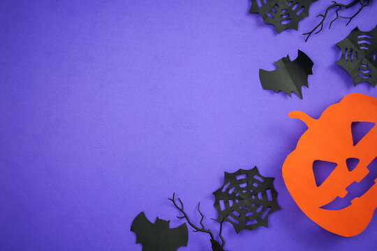 Halloween paper cut jack o lantern and bats on purple background with copy space