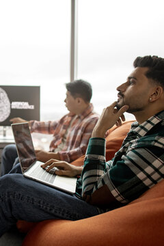 Two men in casual attire are engaged in a discussion about artificial intelligence, with one pointing at a screen displaying AI-related graphics