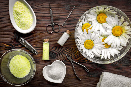 Manicure set with spa salt and chamomile on dark wooden desk top view