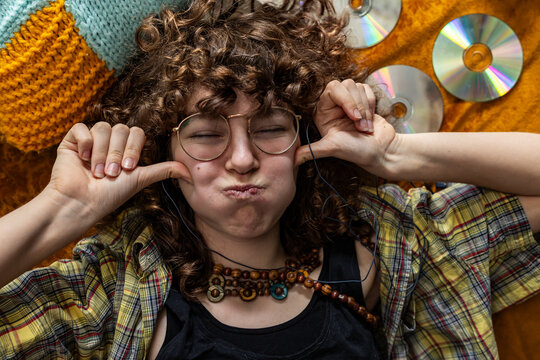 Teenage girl makes a funny face while listening to music indoors