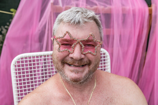 Smiling man wears pink star eyewear during a summer carnival party