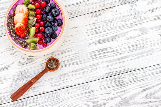 Superfoods. Acai smoothie bowl with fresh fruits, berries, chia seeds on white wooden background top view copy space