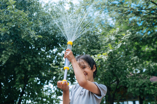 Happy boy plays with a water gun outdoors in summer