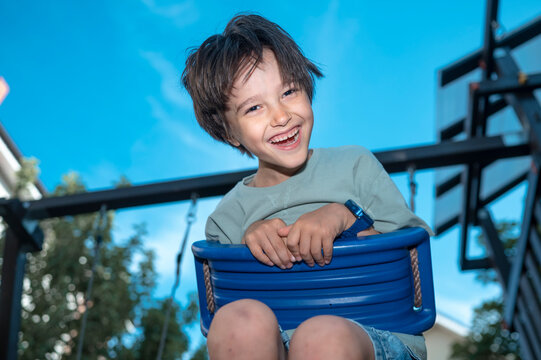 A happy boy enjoys a swing at the outdoor playground