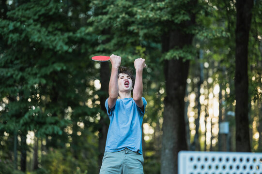 Excited teenage boy celebrates a table tennis victory outdoors