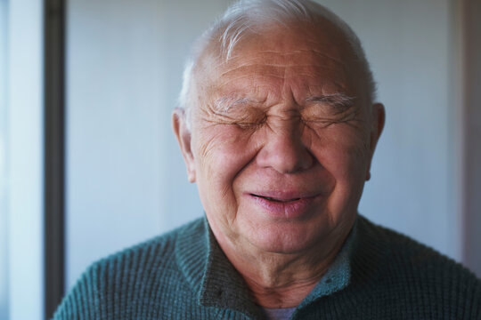 Smiling senior man with eyes closed in peaceful meditation indoors