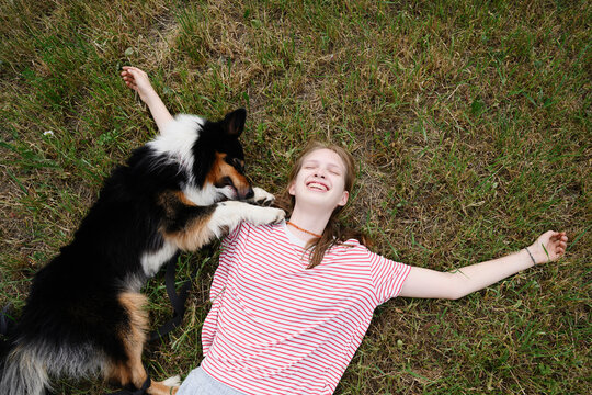 A happy girl plays with her dog on the grass outdoors