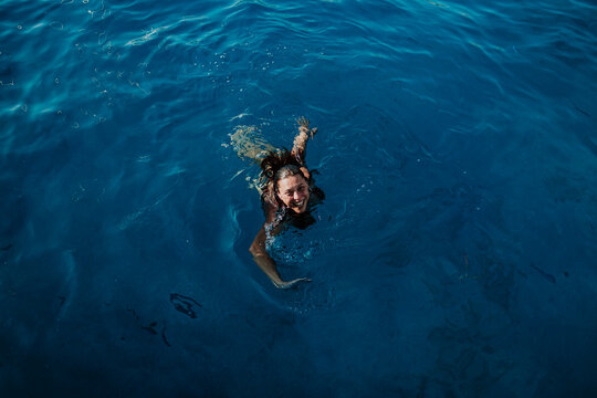 A smiling woman swims in the sea during a summer vacation in Ibiza