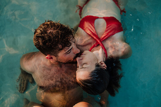 A man and a woman kiss in the sea during a vacation in Ibiza