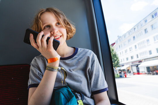 A smiling girl talks on a smartphone during a bus ride