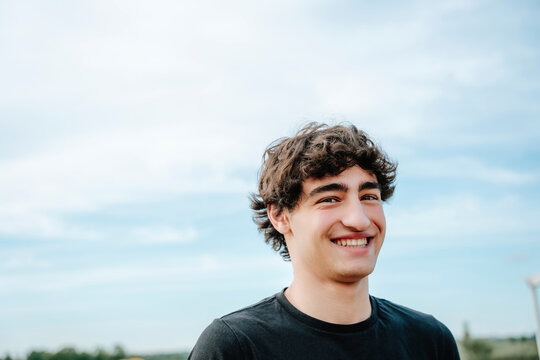 Smiling guy enjoys summer tranquility outdoors under the blue sky