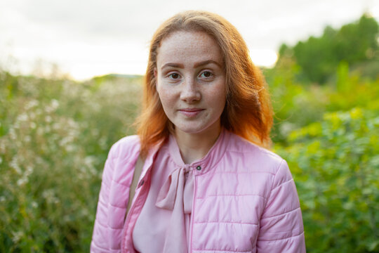 Woman with red hair wears a pink dress outdoors at sunset