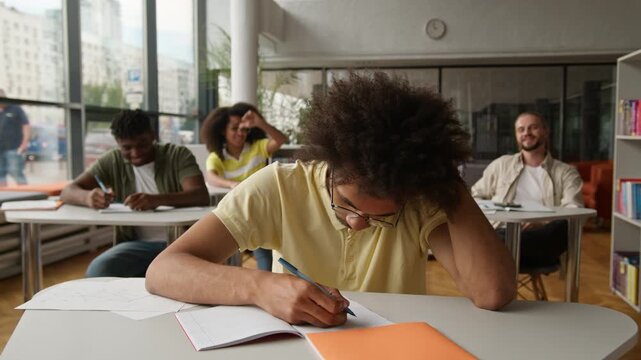 African American student guy sad upset bullying trouble in lesson class ethnic man male frustrated four diversity classmates students throwing paper crumpled balls throw bully in college high school