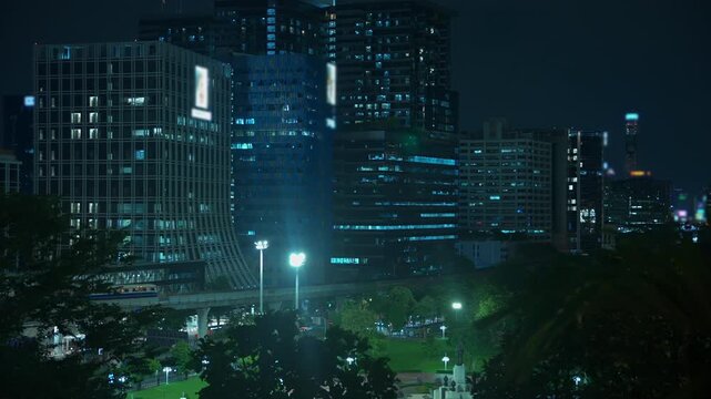 Bangkok skyline at night with BTS Skytrain passing modern skyscrapers, Elevated metro train and illuminated urban cityscape in Thailand 4k