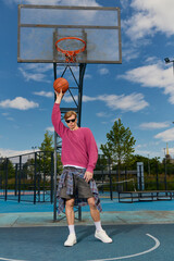 Young man showcases his skills while slam dunking at a vibrant park under a clear sky © LIGHTFIELD STUDIOS