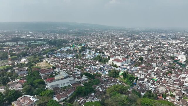 Wide aerial shot of dense urban neighborhoods and greenery in Malang, Java, Indonesia