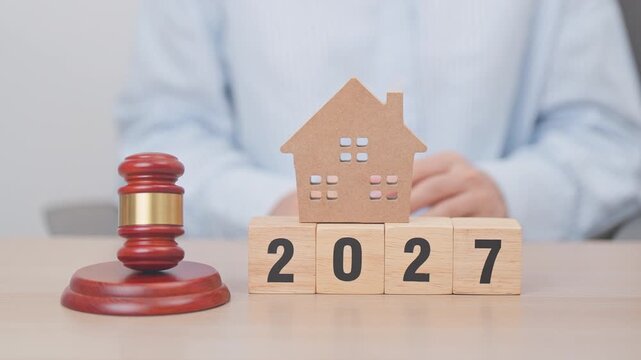 Happy New Year 2027 with small toy house model with gavel justice hammer on desk in courthouse. Real Estate Law, Home Insurance, property Tax, Auction and Bidding concepts