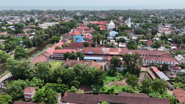 Broad overhead shot illustrating urban backwater integration in Civil Station Ward, Alappuzha. Captures the historic Commercial Canal flanked by CCS SB Road and lush foliage extending