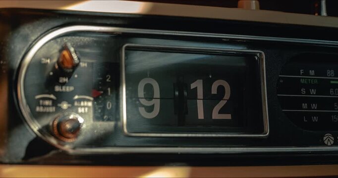 Timelapse of vintage flip clock radio changing numbers with dynamic sunlight streak
