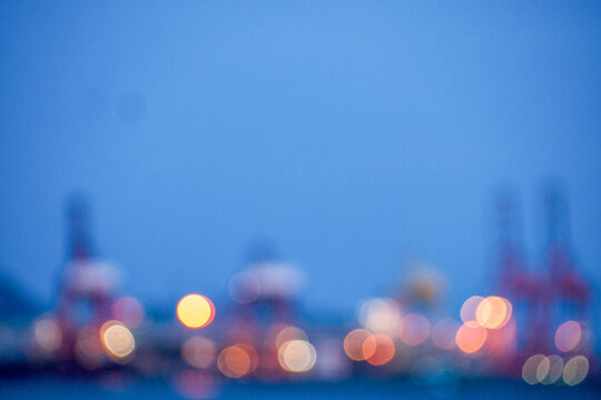 Blurred Background Logistic shipping quay boat in twilight sky night. Defocused blur Engineering crane depot at logistic export terminal seascape ocean Design Element. Warehouse crane background