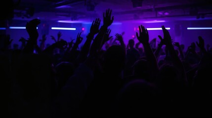 Fototapeta premium Crowd of people dancing at night club with hands in air. Young man and woman silhouettes enjoying music at live concert. Entertainment, rave party, night life and social event concept.