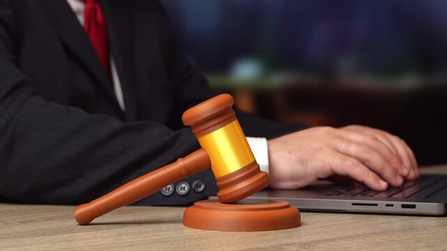 Judge's gavel and a man working on a computer in the background. Lawmaking. Legal reforms, governance debates and public policy education.