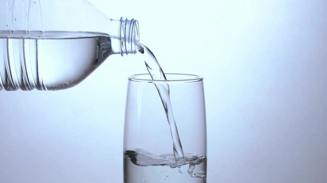 Fresh water pouring into a clear glass on a clean minimal background.