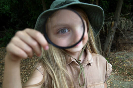 Candid Portrait of Curious Girl Playing with Magnifying Glass