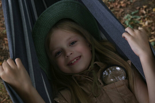 Candid Childhood Portrait of Happy Girl Looking at Camera from Hammock