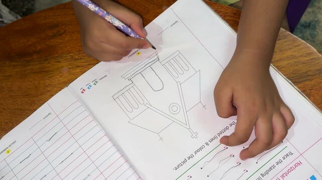 Child Practicing Pencil Tracing On Dotted Worksheet At Home