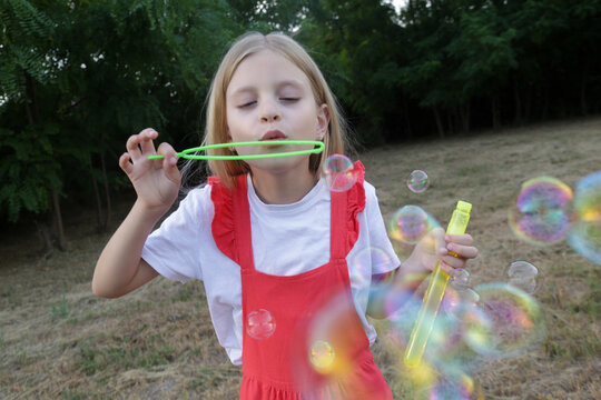 Happy little girl blowing soap bubbles on a sunny summer day