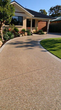 Modern driveway with exposed aggregate concrete leading to a suburban home. Ideal for exterior residential property.
