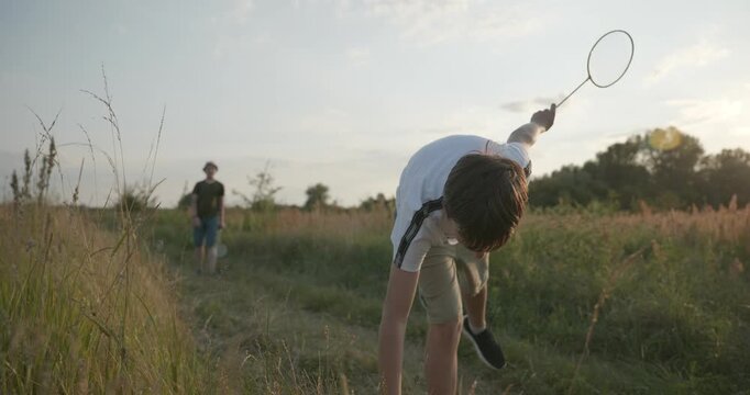 Two boys play badminton on nature. Teenagers spending time together. 4K 10-bit