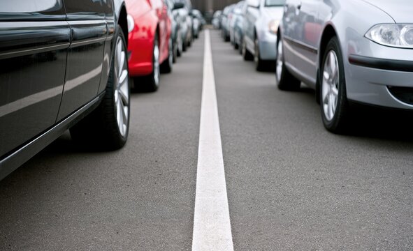 Two rows of parked cars, black and red on left, silver on right, divided by a line