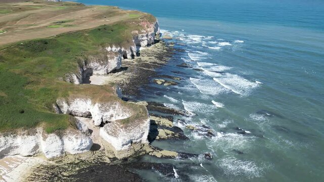 Aerial rising view over scenic white chalk cliffs and ocean waves at Flamborough, England