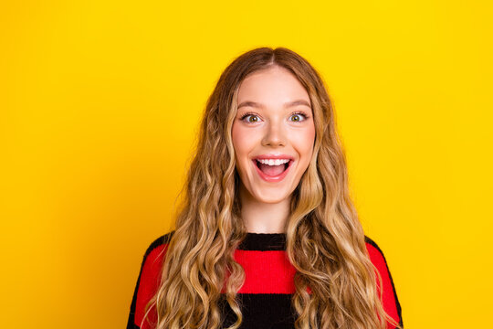 Beautiful girl in striped sweater smiles with excitement against yellow background capturing vibrant and cheerful moments