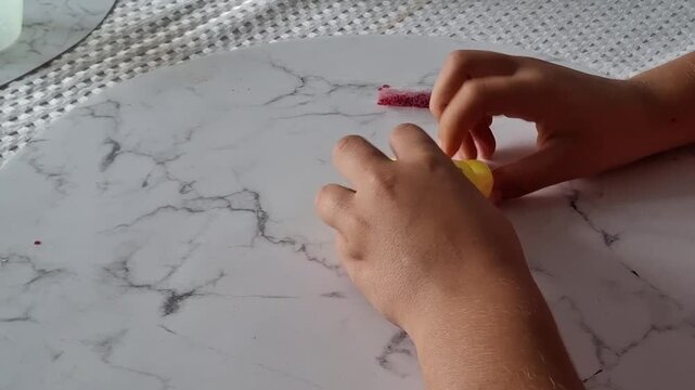 Child plays with yellow slime on a marble surface in a bright room during daytime