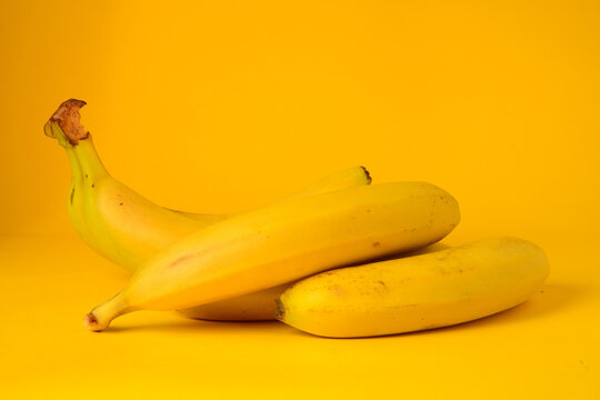 Platanos frescos sobre un fondo amarillo. Concepto de alimentaci&oacute;n saludable, bebida refrescante, fruta de verano y fotograf&iacute;a de producto en estudio 