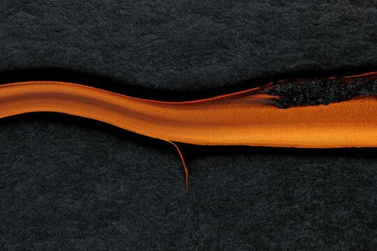 Molten orange fluid flowing and crackling against a dark, textured background