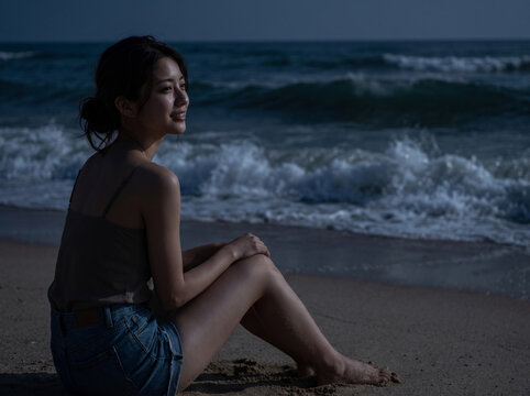 夜の海岸で穏やかに微笑みながら波音に耳を傾ける女性