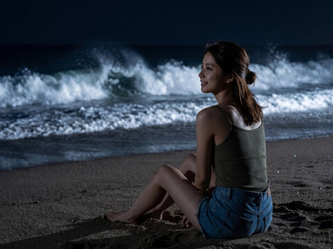 夜のビーチでリフレッシュするタンクトップ姿の女性
