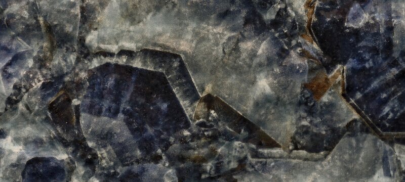 A close-up of a polished sodalite slab, displaying rich royal blue and greyish-white crystalline patterns with dark angular veining.It uses in ornamental carvings, countertops and mosaic tiles.