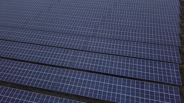 Aerial drone view highlighting the dark surface of solar panels installed in a rural meadow in Drenthe, Netherlands. This shot is part of a series showcasing local solar parks generating  energy
