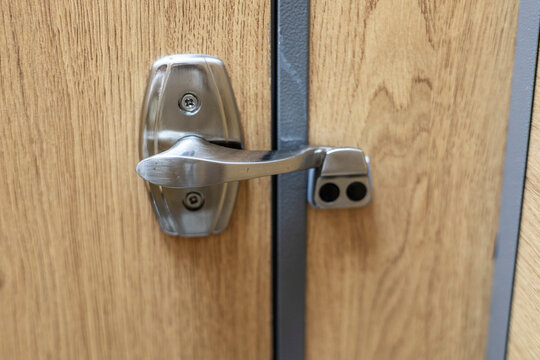 Metal door latch mounted on a wooden door, home security hardware, privacy, access control, functional architecture, repair concept.