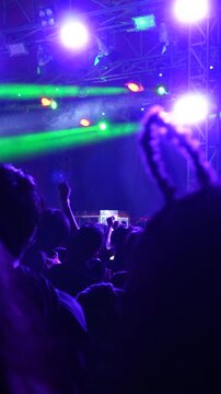 Vertical video of a crowded concert with colorful stage lights at night