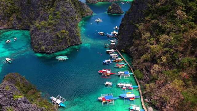 Aerial drone view of the turquoise lagoon at the entrance to Kayangan Lake in Coron, Palawan, Philippines. Traditional boats surrounded by dramatic limestone cliffs and tropical scenery.