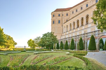 Beautiful manicured garden and floral displays in front of the historic Mikulov Castle in South Moravia, Czech Republic. Elegant baroque garden architecture with green hedges, flowerbeds, and arches u © Igor